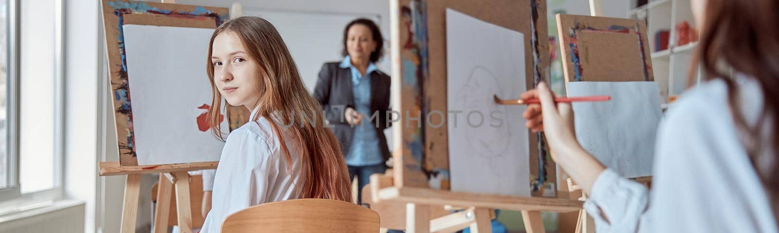 Young caucasian beautiful girl is looking at camera in a group drawing lesson by Yaroslav_astakhov