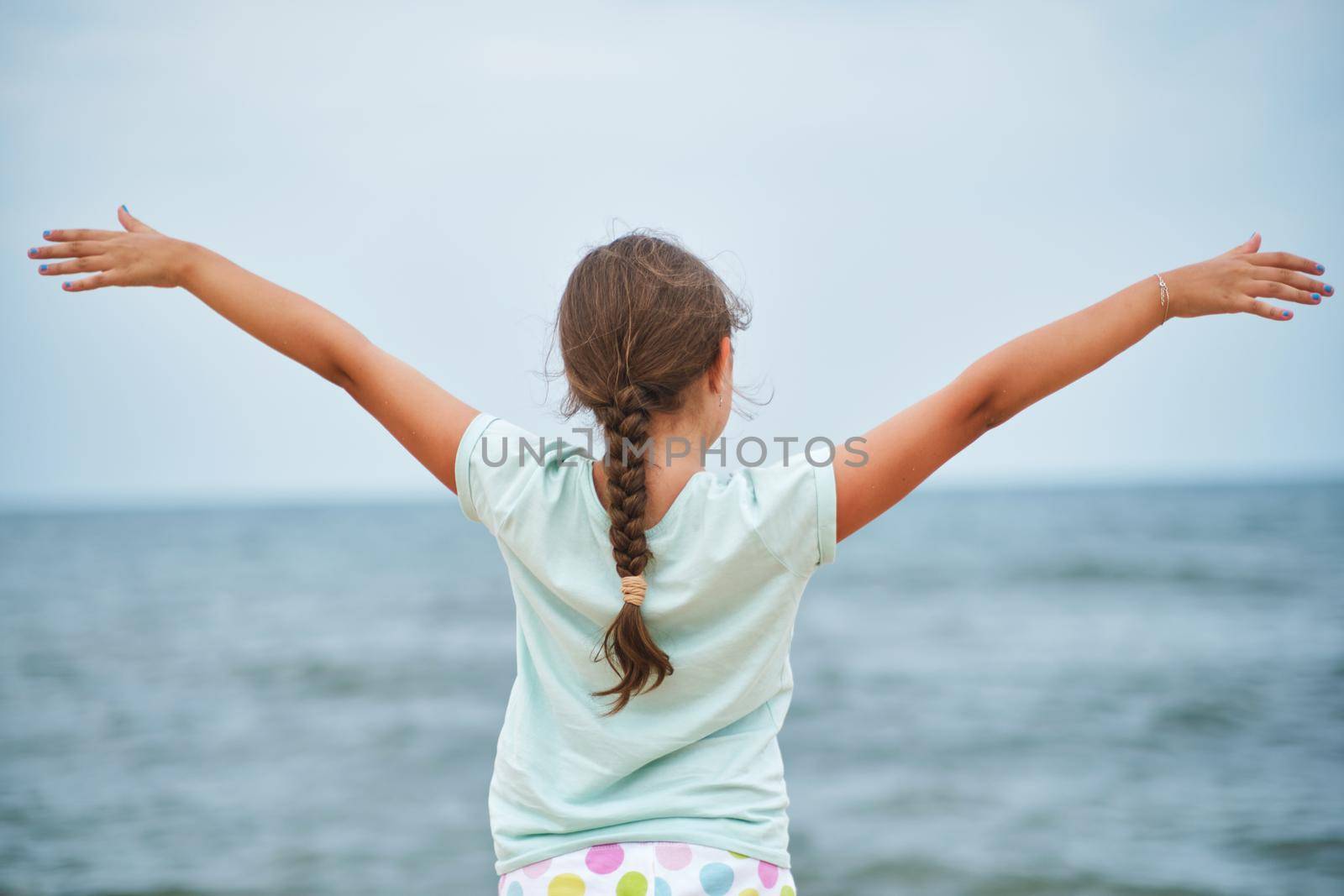 Happy child looking at the sea. Kid girl having fun at the beach. Summer vacation and active lifestyle concept