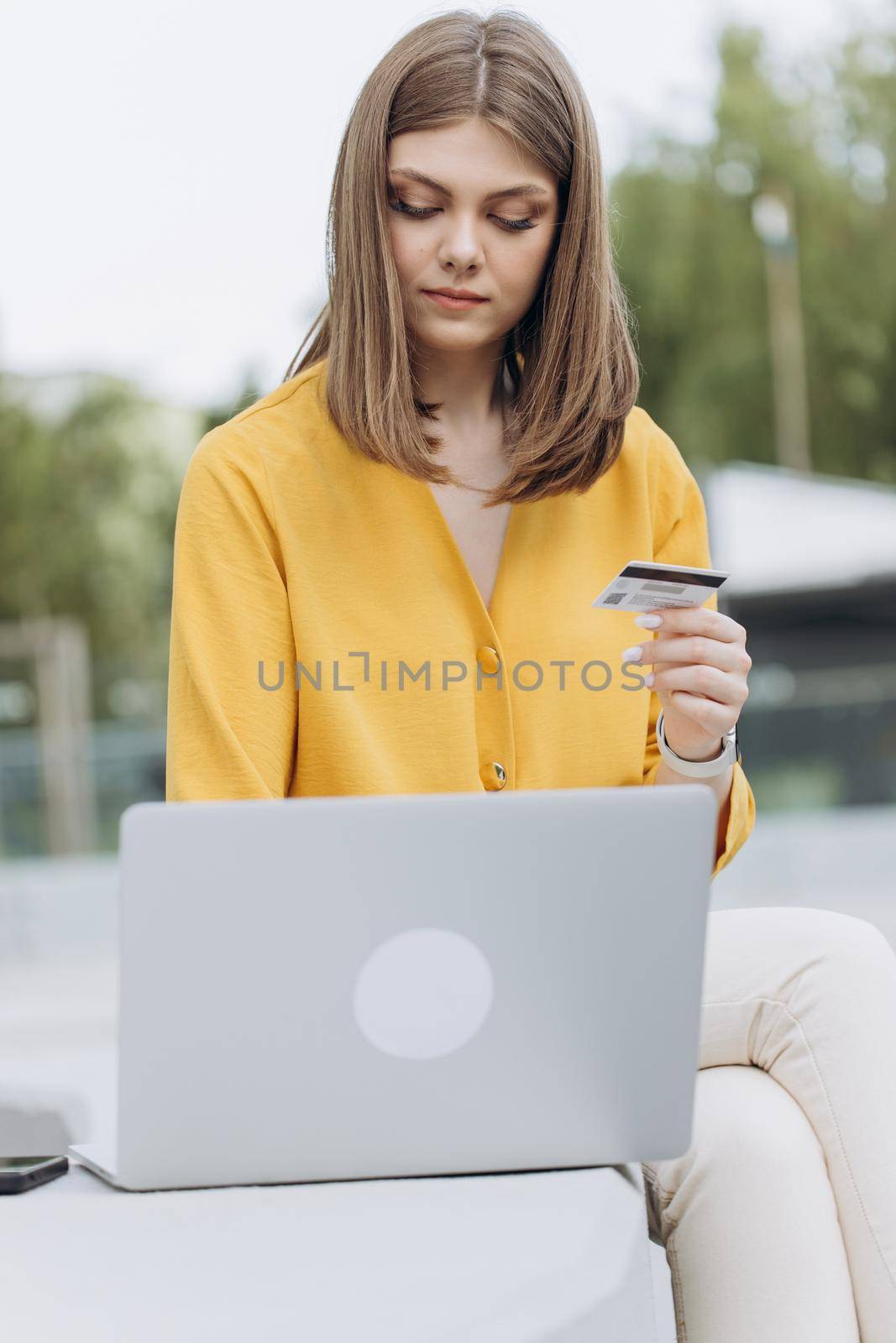 Caucasian woman holding credit card using a digital mobile device and buying online, internet shopping. Female hand typing bank card number into a smartphone by uflypro