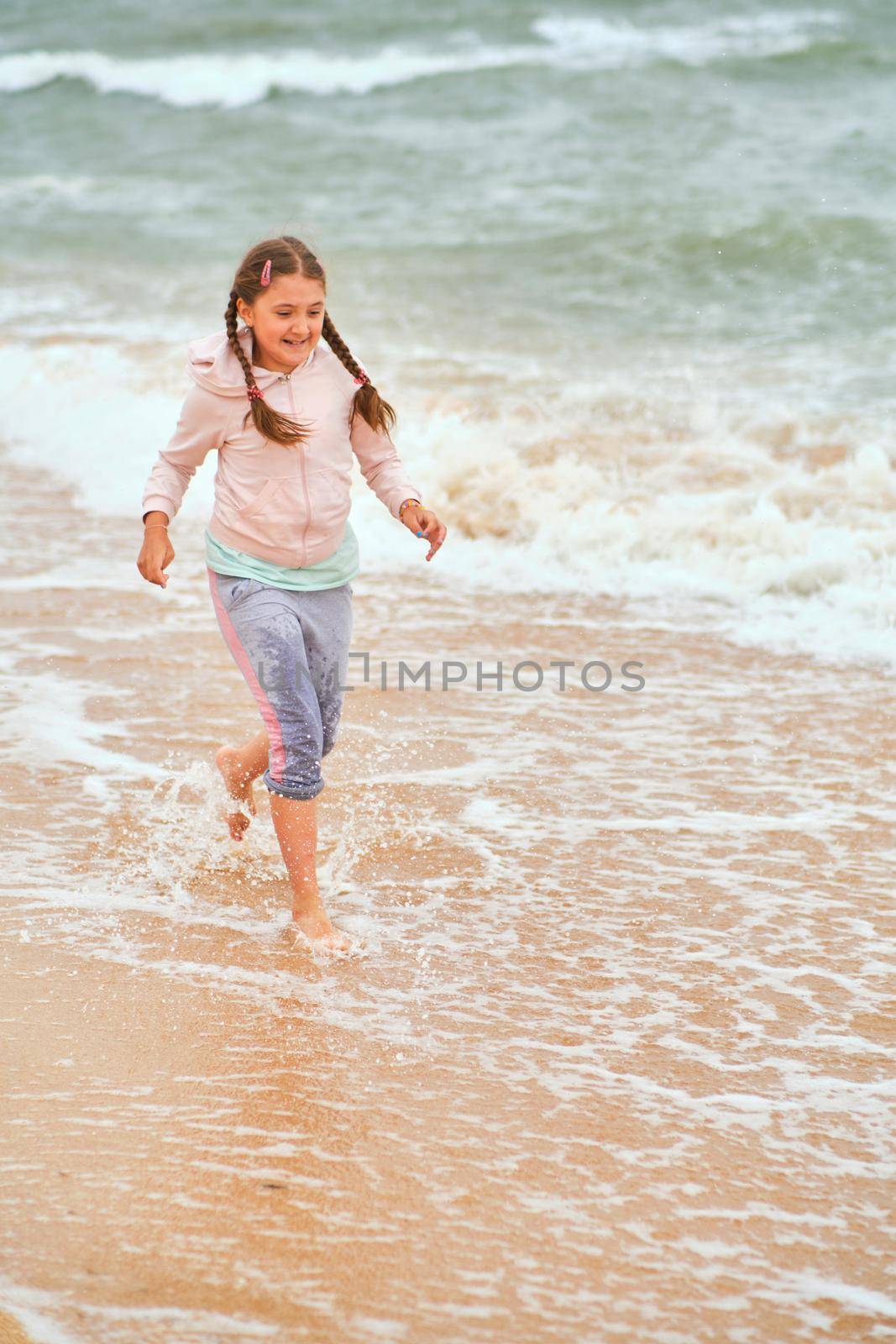 Happy child playing in the sea. Kid girl having fun at the beach. Summer vacation and active lifestyle concept