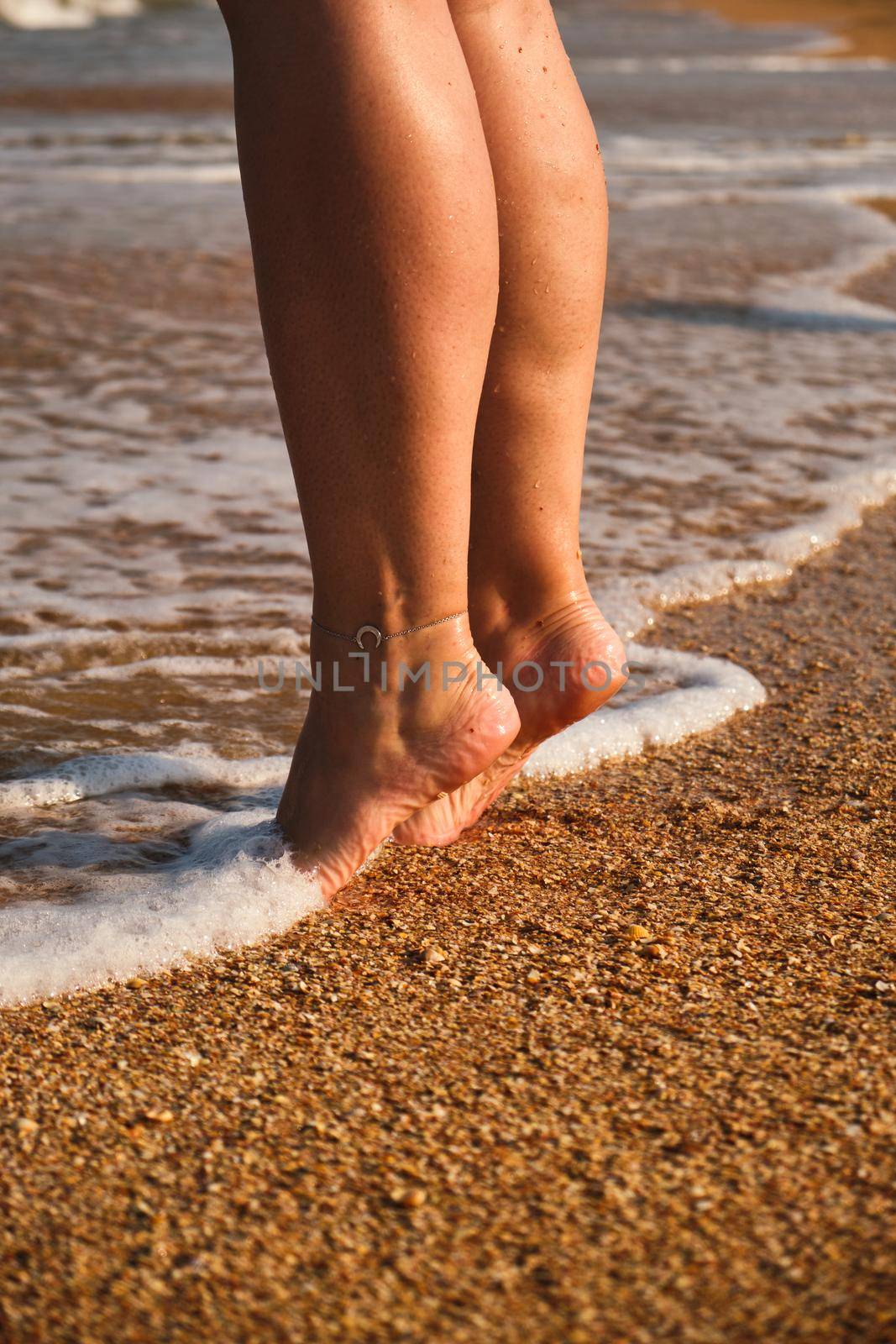 The woman's legs close up. Barefoot on the sand and the sea shore. A woman's feet a woman walks along the coast of the sea. lifestyle