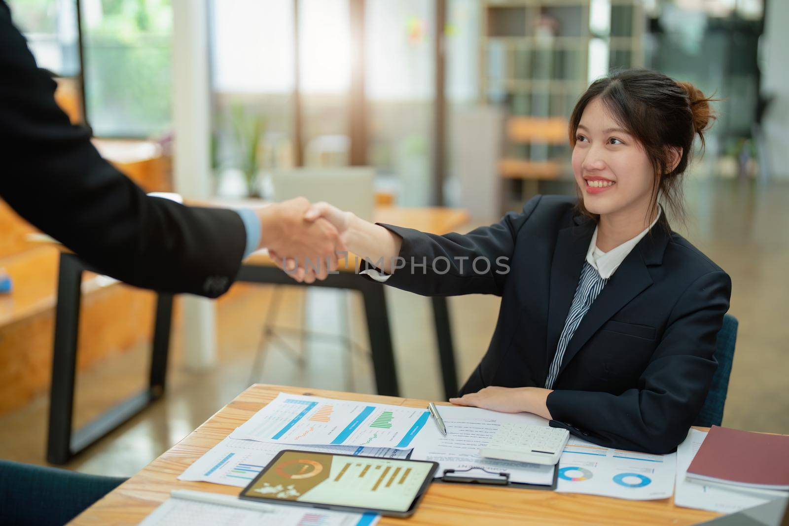 Asian entrepreneurs handshakes to congratulate the agreement between the two companies to enhance investment and financial strength. deal concept by Manastrong