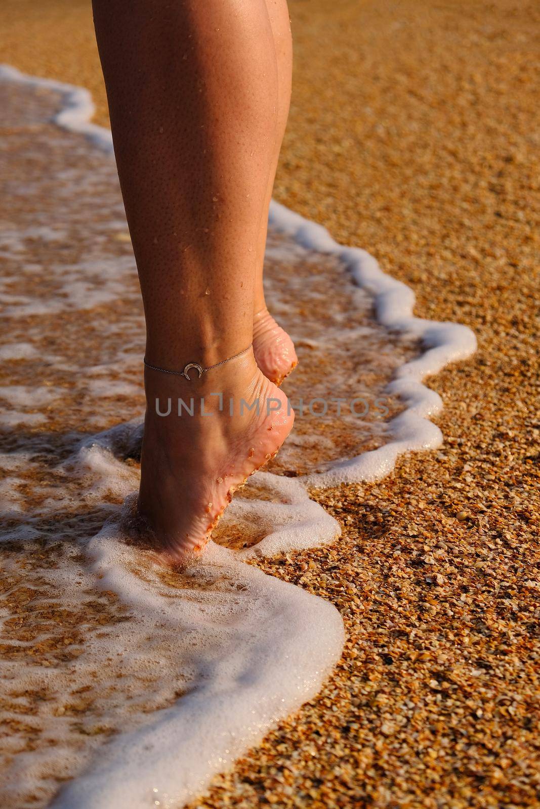 The woman's legs close up on the sand and the sea shore. by InnaVlasova