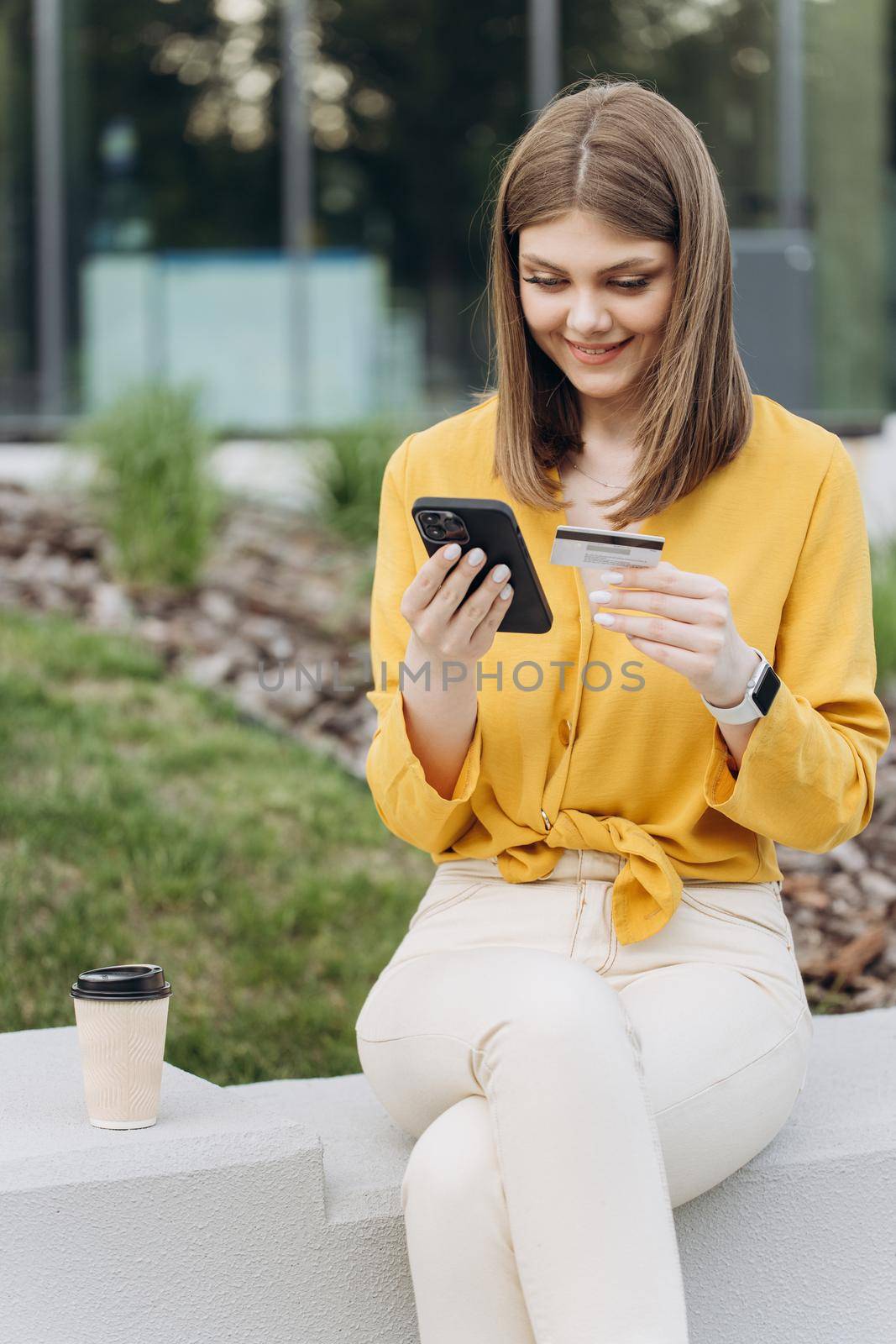 Female hand typing bank card number into a smartphone. Vertical shot of young white caucasian woman holding credit card using a digital mobile device and buying online, internet shopping by uflypro