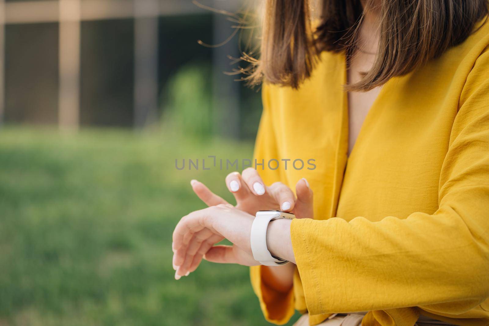 Caucasian woman use her wearable smart watch and smiling. Smart watch. Smart watch on a woman's hand outdoor. Appealing young elegant woman touching a smartwatch.