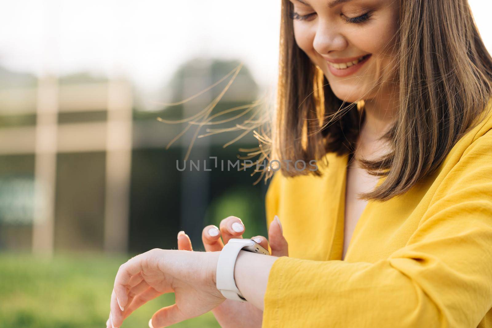 Smart watch. Smart watch on a woman's hand outdoor. Appealing young elegant woman touching a smartwatch. Caucasian woman use her wearable smart watch and smiling by uflypro
