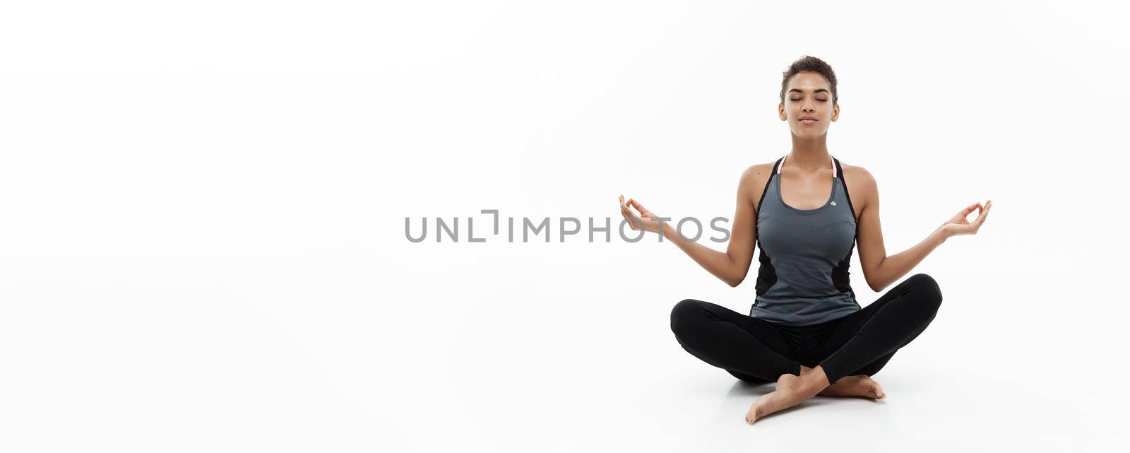 Healthy and Fitness concept - Beautiful American African lady in fitness clothing doing yoga and meditation. Isolated on white background