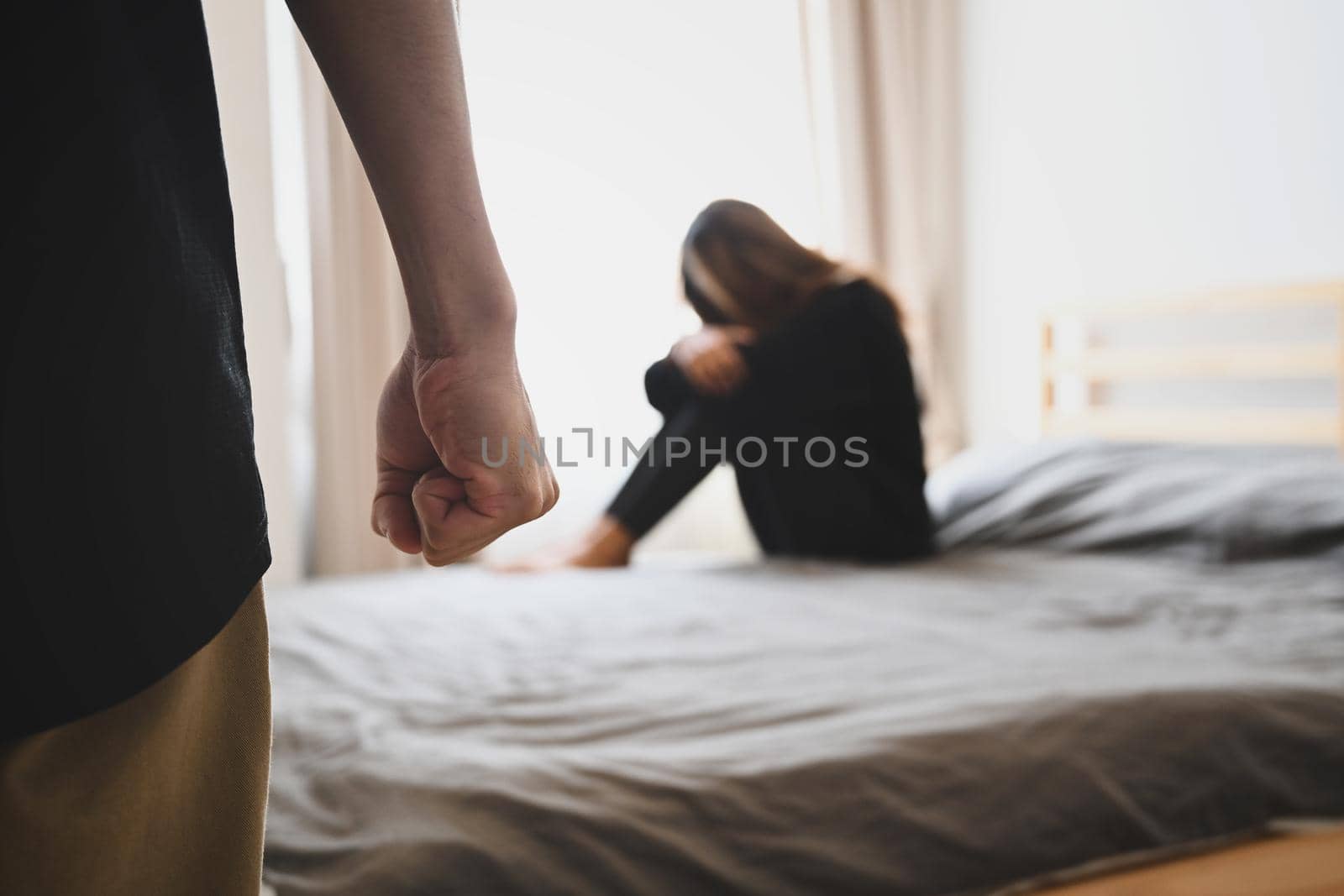 Cropped image of man clenching fist in anger with crying woman in background. Domestic Family violence concept. by prathanchorruangsak