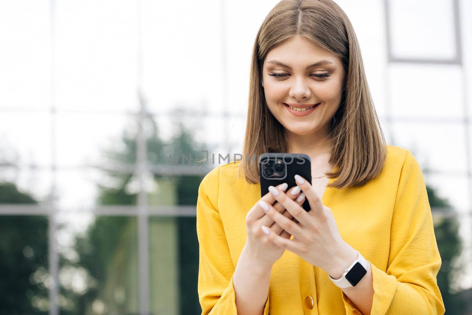 People portraits and technology concept. Appealing young elegant caucasian woman using social media application on smartphone text messages receive news smiling outdoor by uflypro