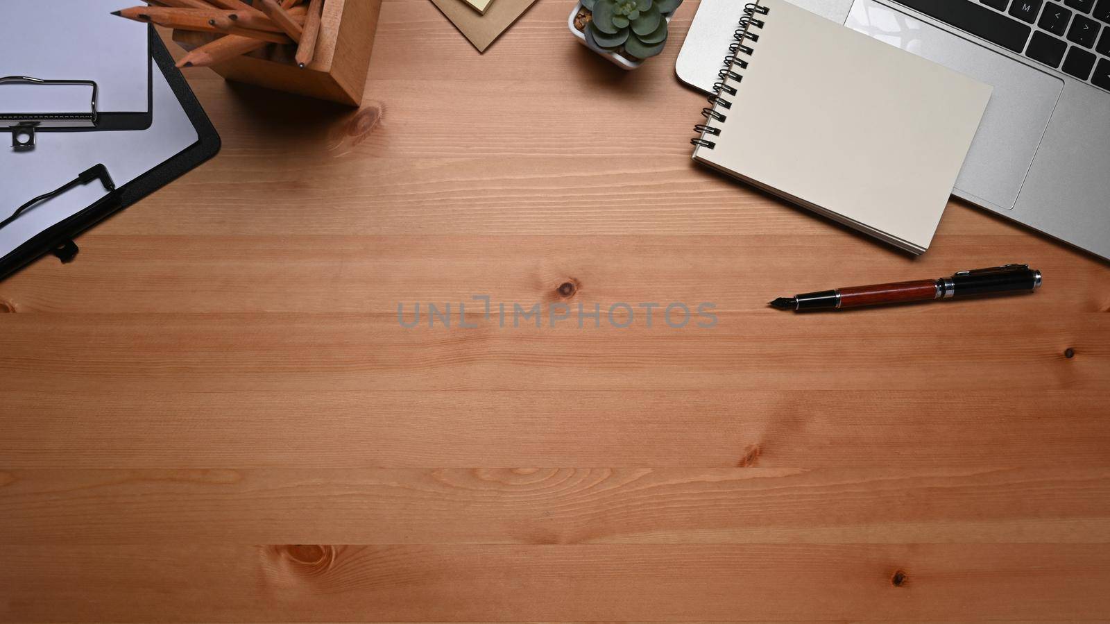 Above view, laptop computer, notepad, pen and succulent plant on wooden table.