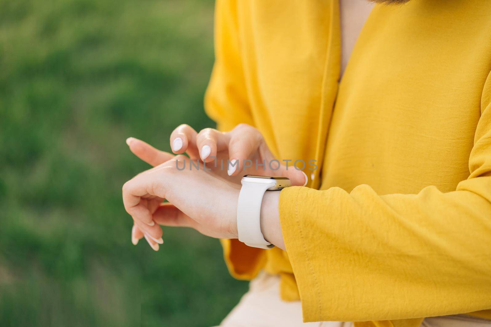 Smart watch on woman's hand outdoor. Woman's hand touching a smartwatch. Female's hand uses of wearable smart watch at outdoor.