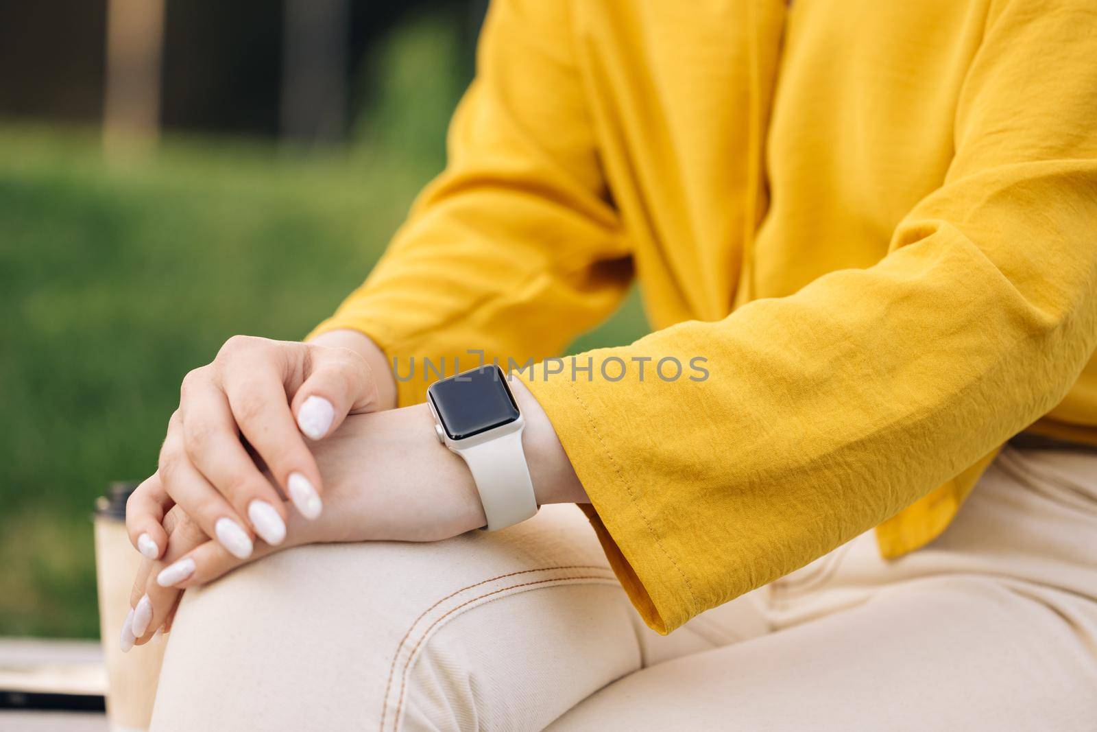 Smart watch on woman's hand outdoor. Woman's hand touching a smartwatch. Female's hand uses of wearable smart watch at outdoor by uflypro