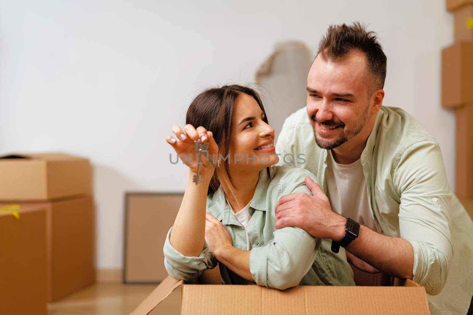 Young happy couple in room with moving boxes at new home by Fabrikasimf