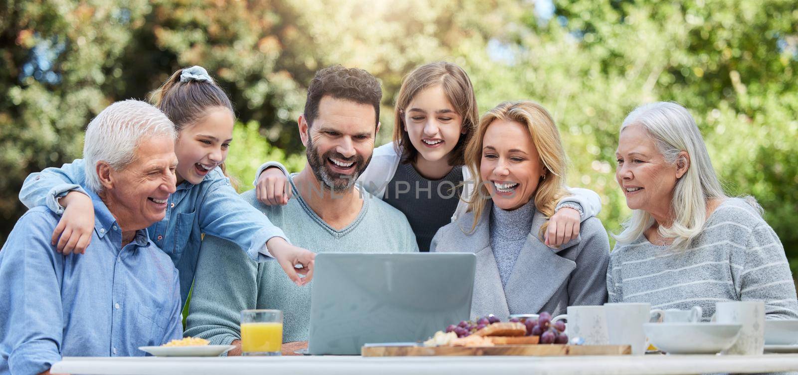 Shot of a family using a laptop outside.