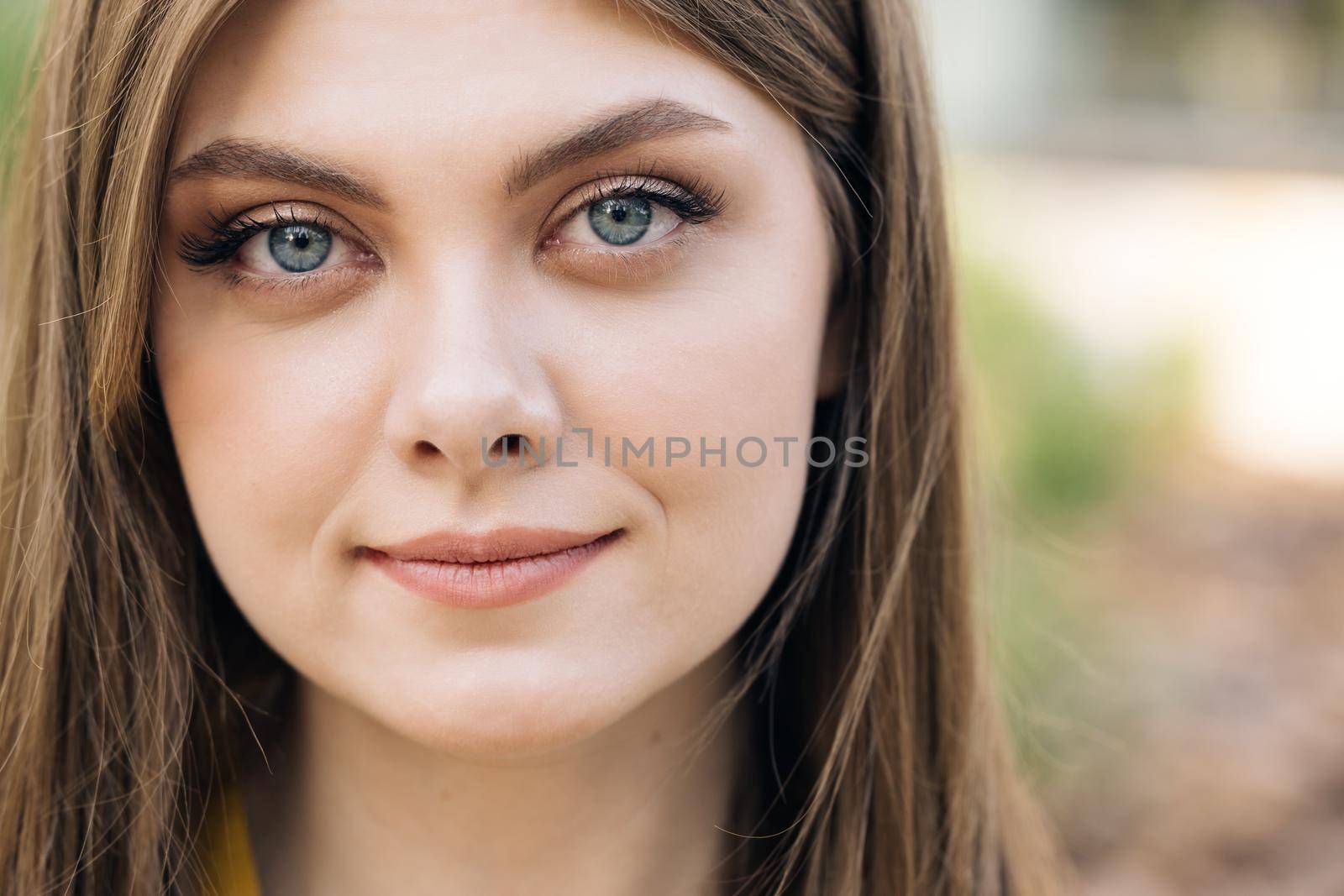 Close up face young woman with brunette hair look at camera smile stand in the city streets. Summer beautiful lady portrait happy outdoor.