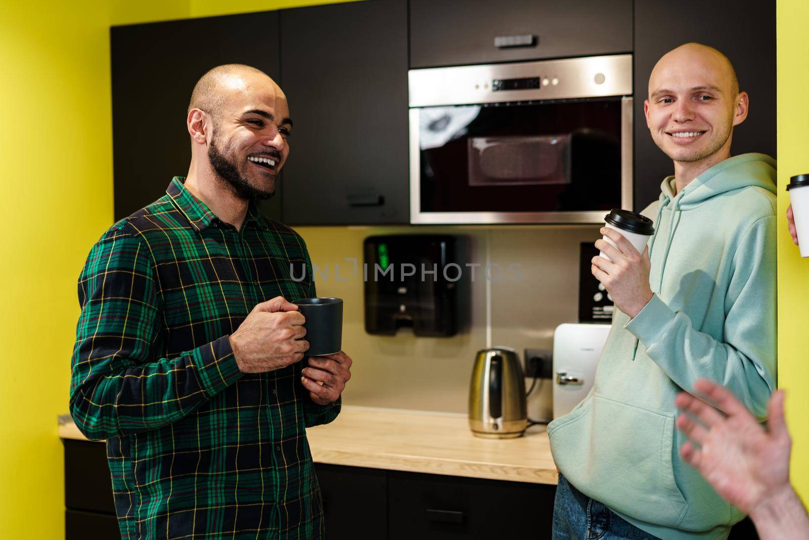 Two male colleagues having a talk while coffee break in office, close up