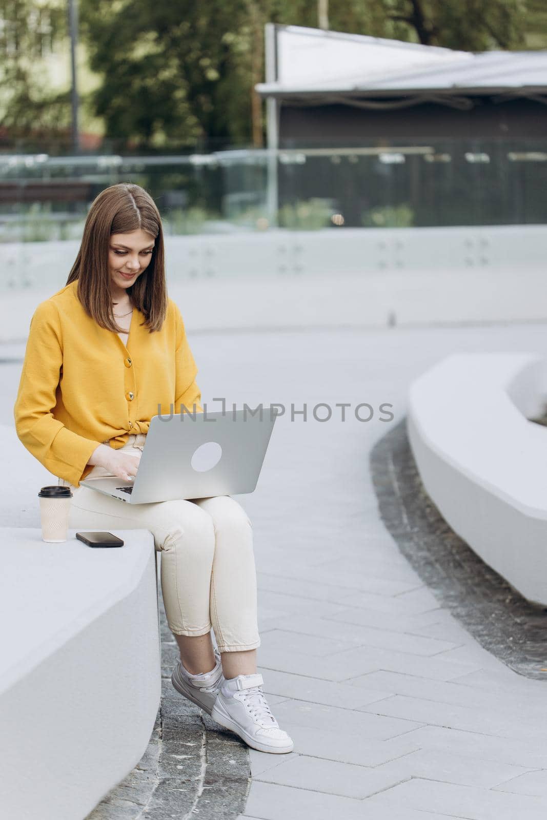 Happy business woman typing on laptop keyboard. Smiling businesswoman using laptop computer for work outside office. Positive female professional reading document at laptop screen outdoors.