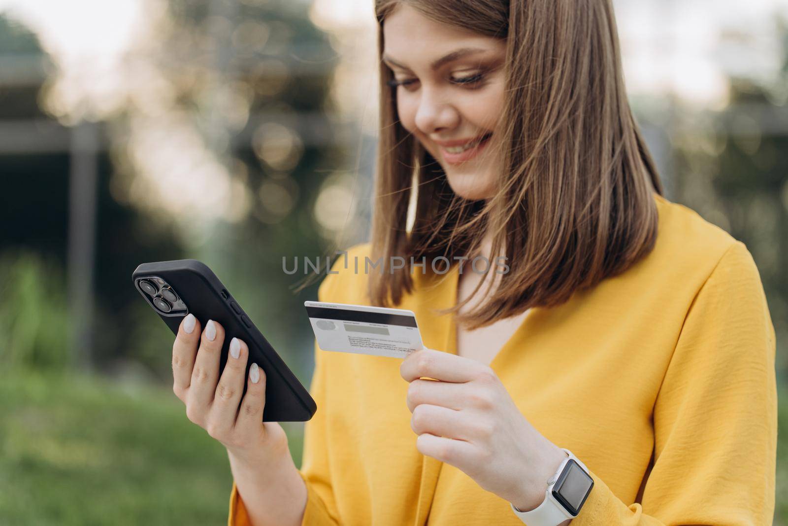 Young woman paying online, using banking service, entering information, shopping, ordering in internet store, doing secure payment. Close up female hands holding credit card and smartphone.