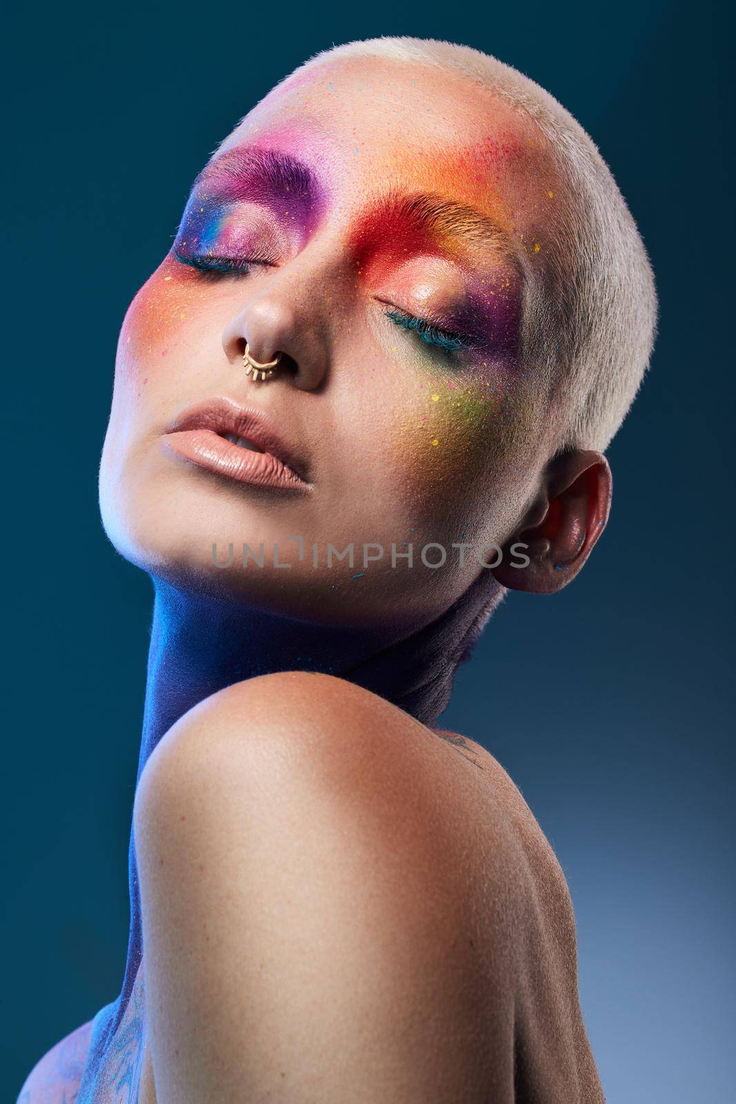 Be you. Be different. Studio shot of a young woman posing with multi-coloured paint on her face. by YuriArcurs