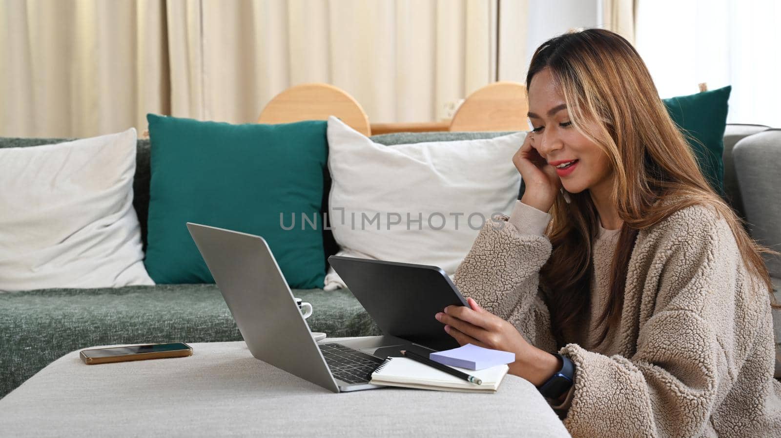 Happy young asian woman working with laptop computer and digital tablet at home.