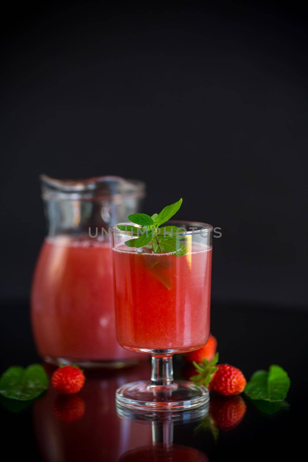 Cold summer strawberry kvass with mint in a glass isolated on black background