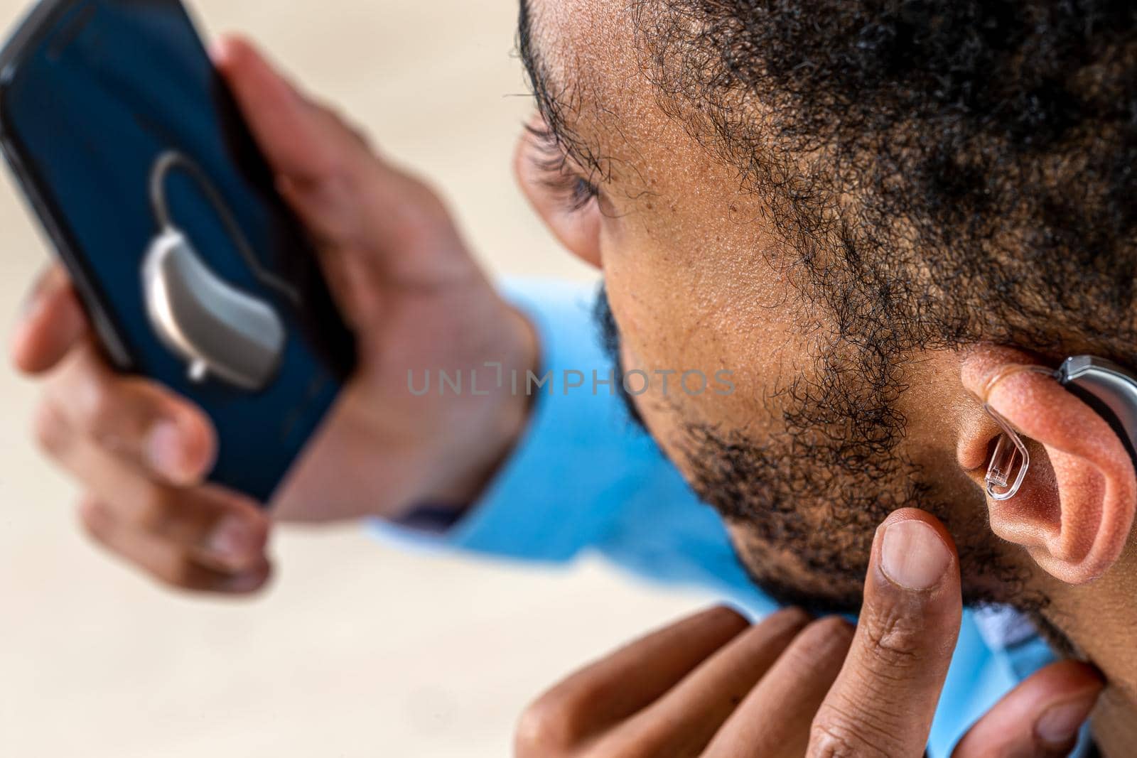 Young man adjusts the intensity of the volume of the auditory headset with the smartphone