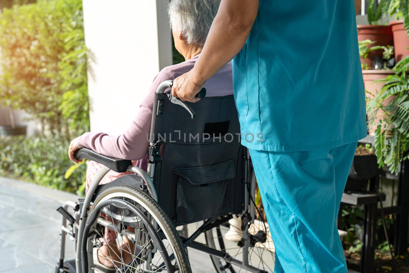 Caregiver help and care Asian senior or elderly old lady woman patient sitting in wheelchair on ramp at nursing hospital, healthy strong medical concept