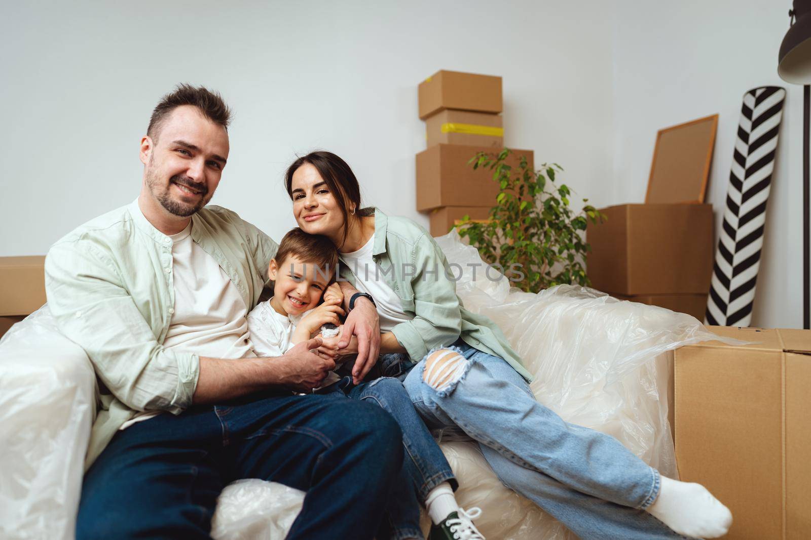 Young parents and son having fun during moving day to new house, portrait