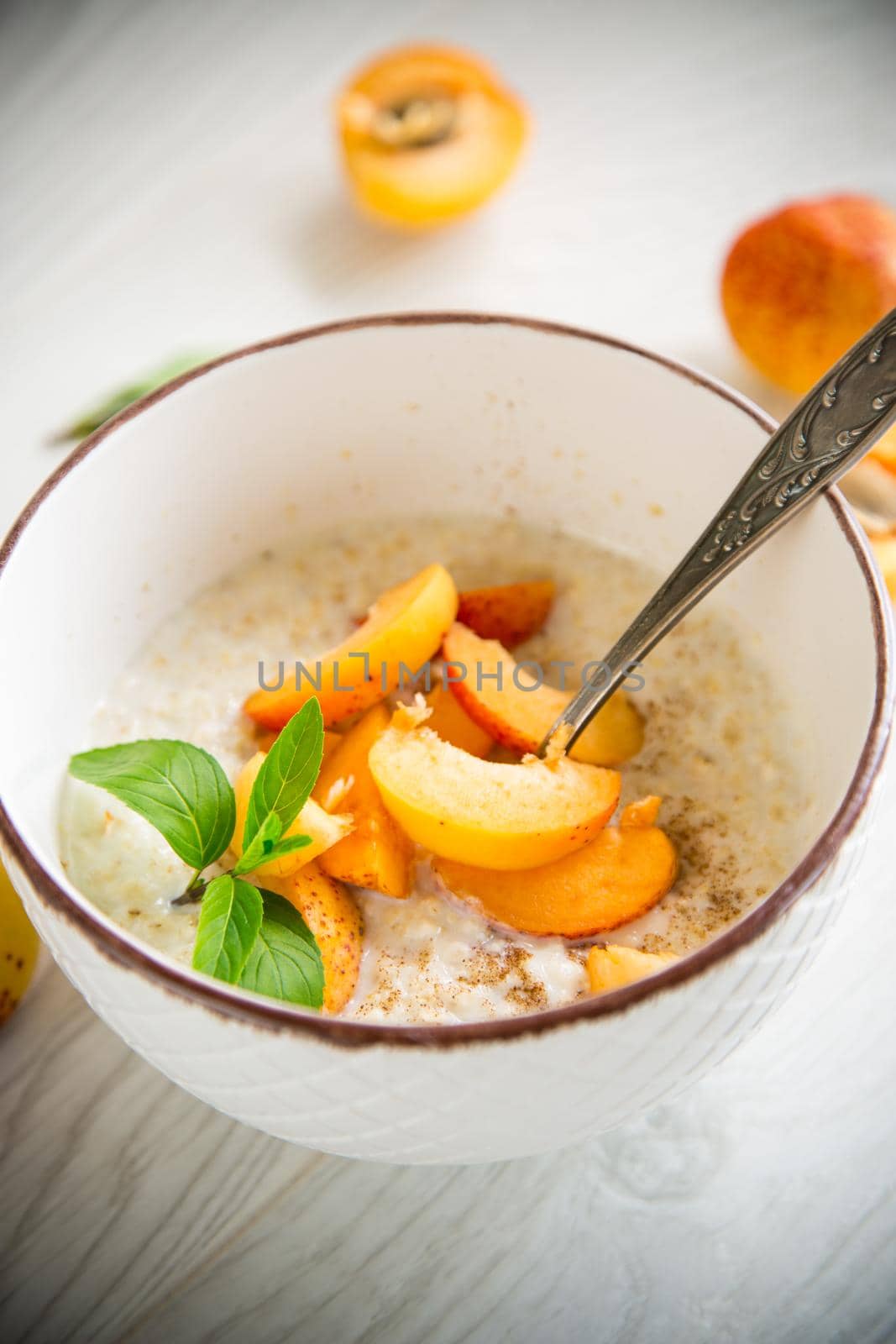 Healthy breakfast of boiled oatmeal with fresh apricots in a bowl on the table.