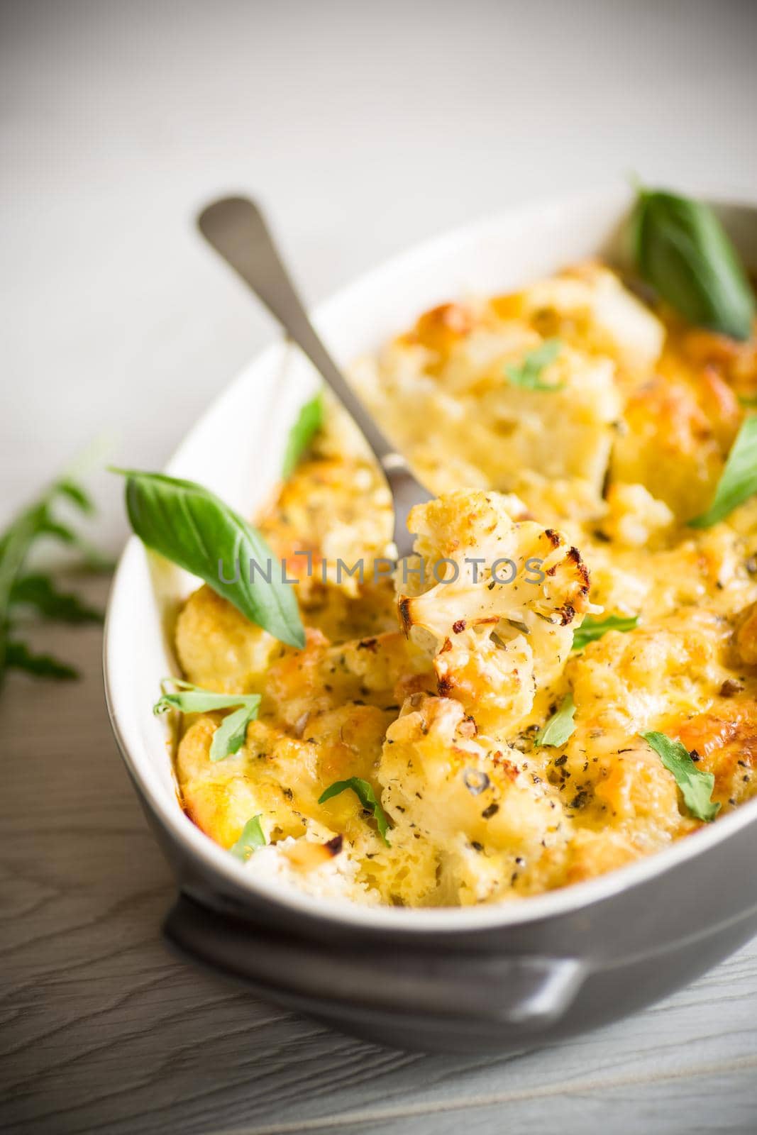 baked cauliflower with vegetables and cheese and scrambled eggs in a ceramic dish