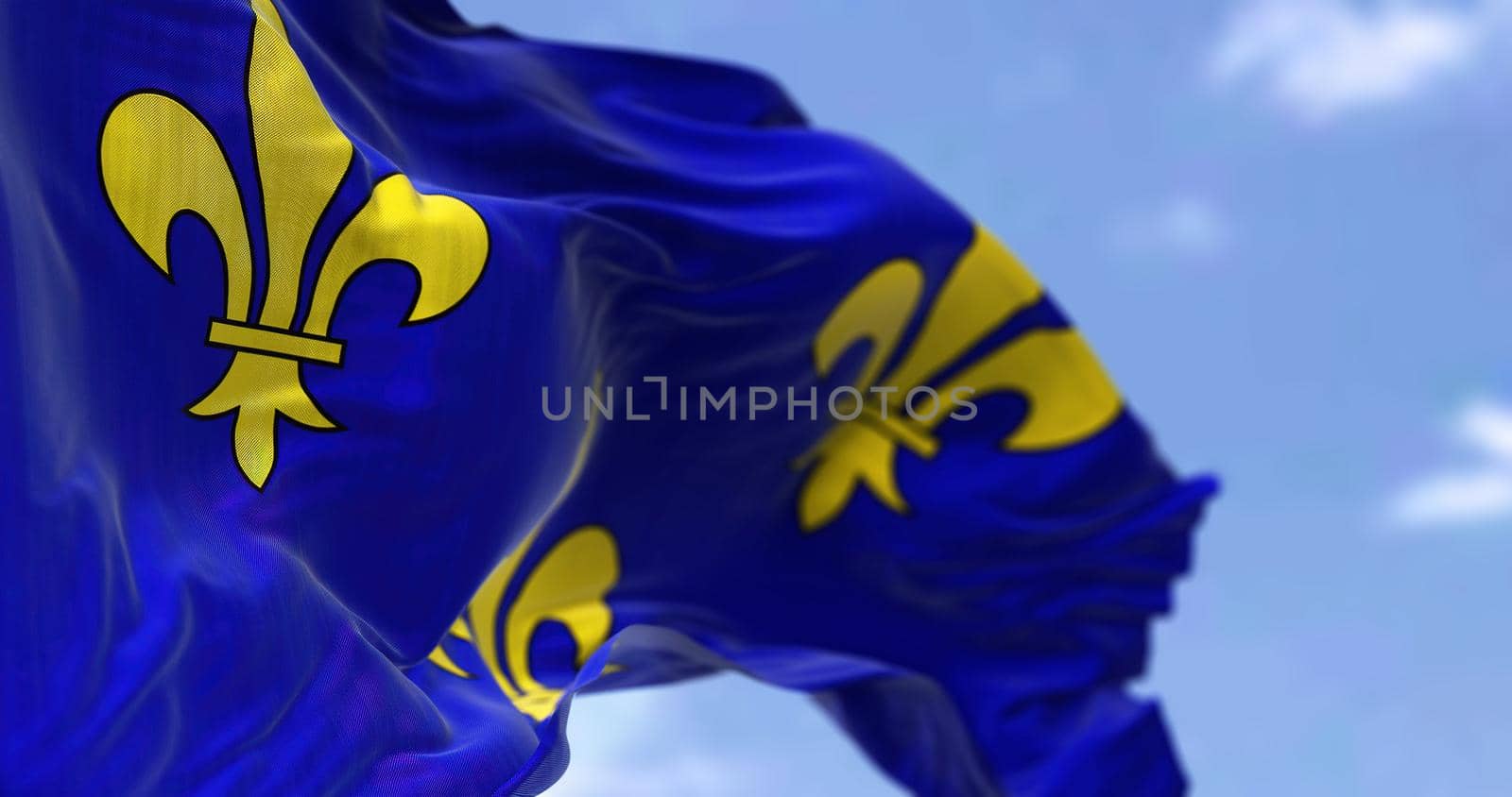 The flag of Ile de France region waving in the wind on a clear day. Ile de France is the most populous of the eighteen regions of France by rarrarorro