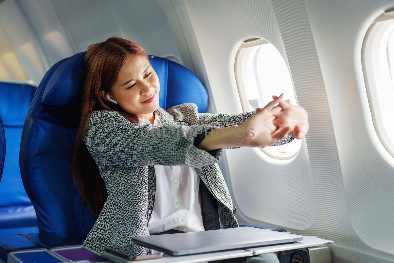 Portrait of a successful Asian businesswoman or entrepreneur in a formal suit on an airplane in business class waking up from resting between flights.