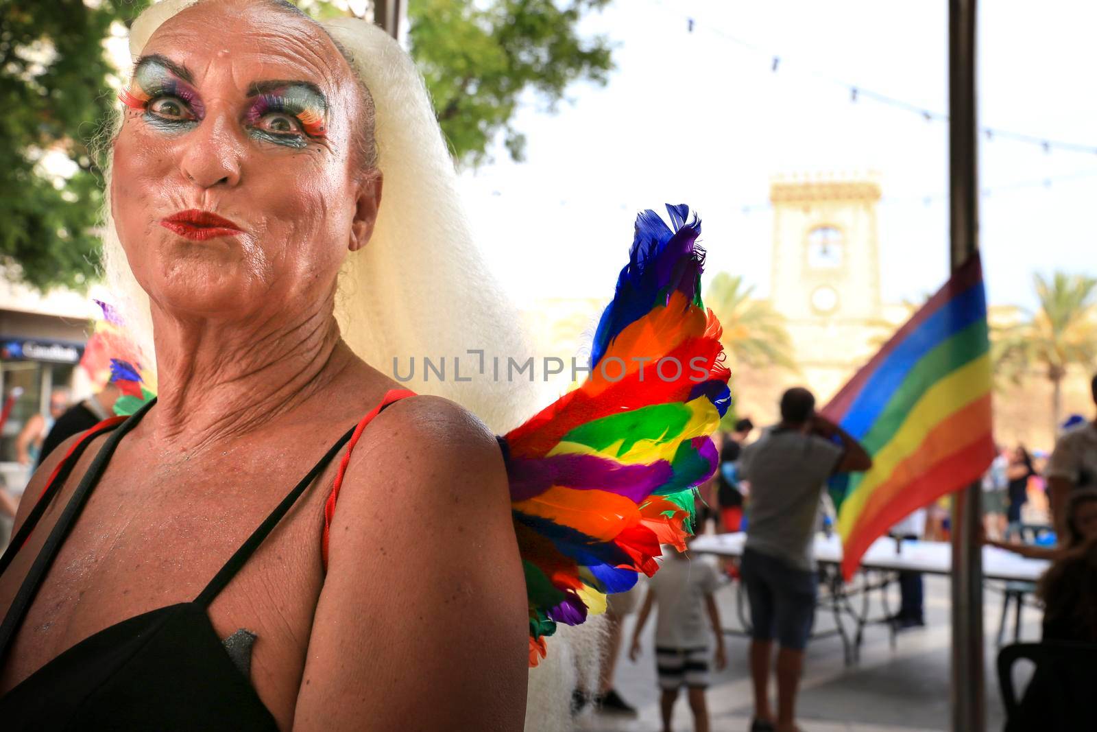 Santa Pola, Alicante, Spain- July 2, 2022: Spanish People attending Gay Pride Parade with rainbow flags, banners and colorful costumes