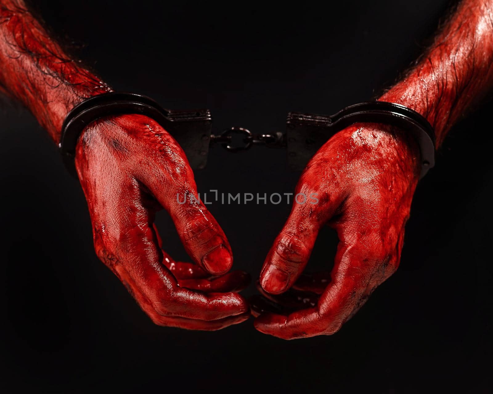 Close-up of male bloody handcuffed hands on a black background