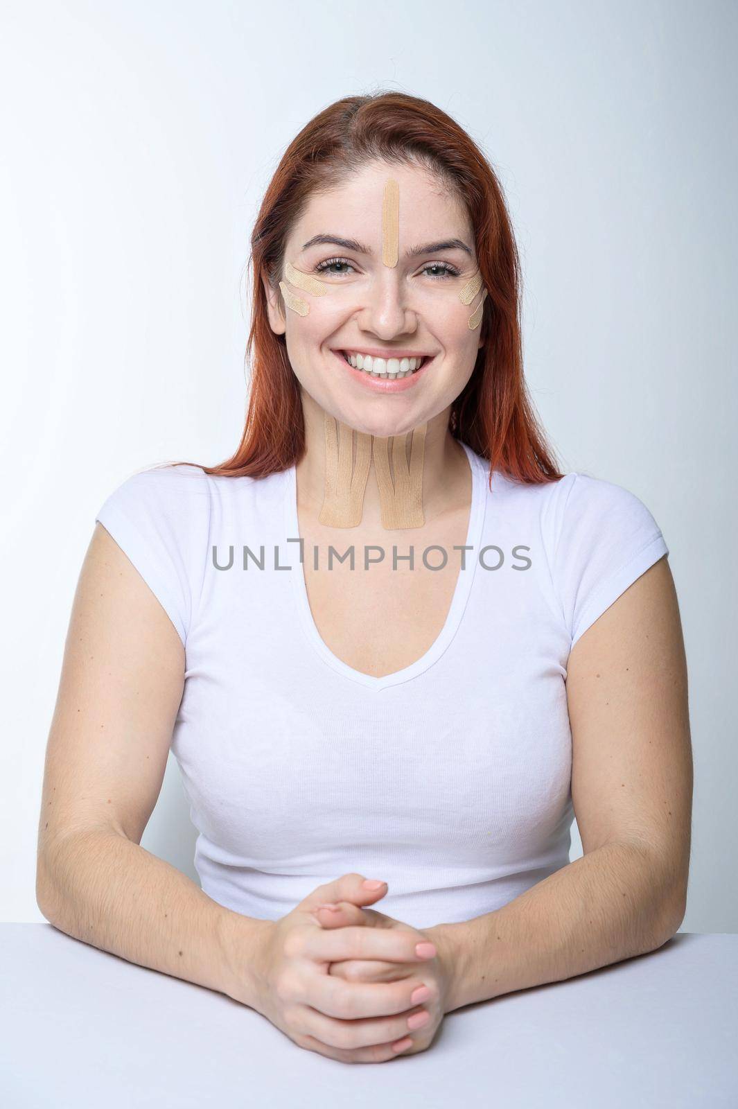 Portrait of a redhead woman with tapes on skin color face for rejuvenation. An alternative way to fight wrinkles. by mrwed54