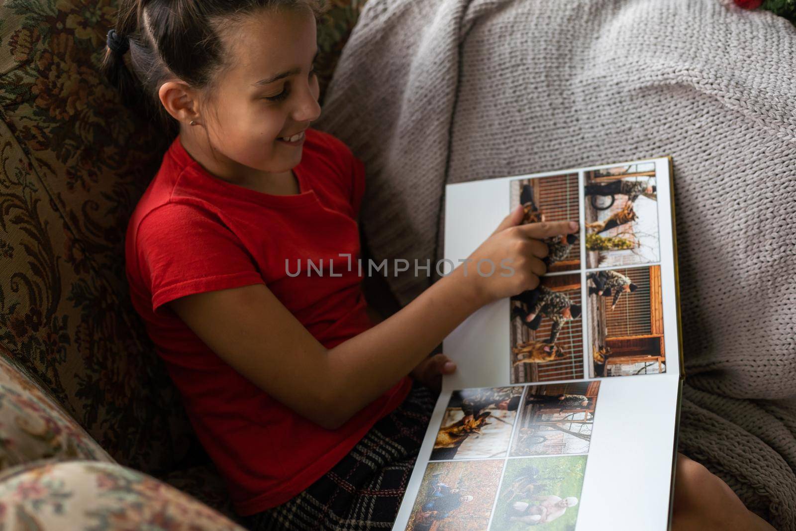 a little girl looking at a photo album in the living room.
