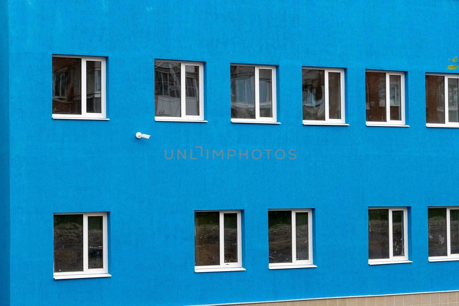 the wall of a new blue house with windows and a surveillance camera. The blue wall. modern architecture. background