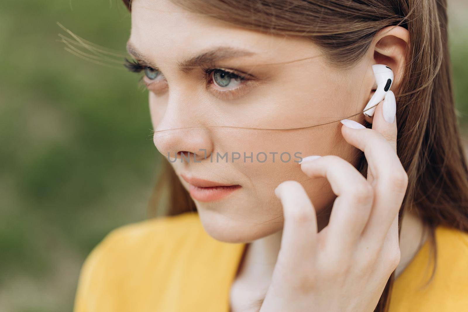 Close up of female ear with wireless earphone inside listening to music. Young beautiful woman with wireless earphones on her ears by uflypro