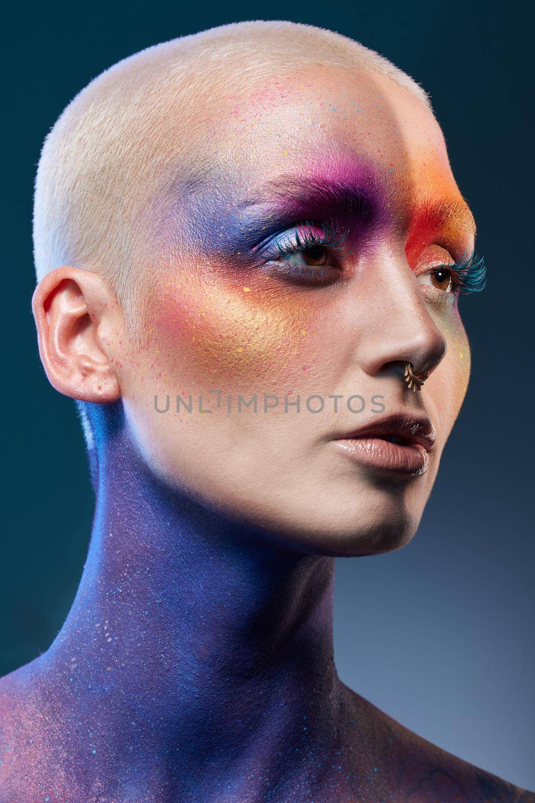 Studio shot of a young woman posing with multi-coloured paint on her face.