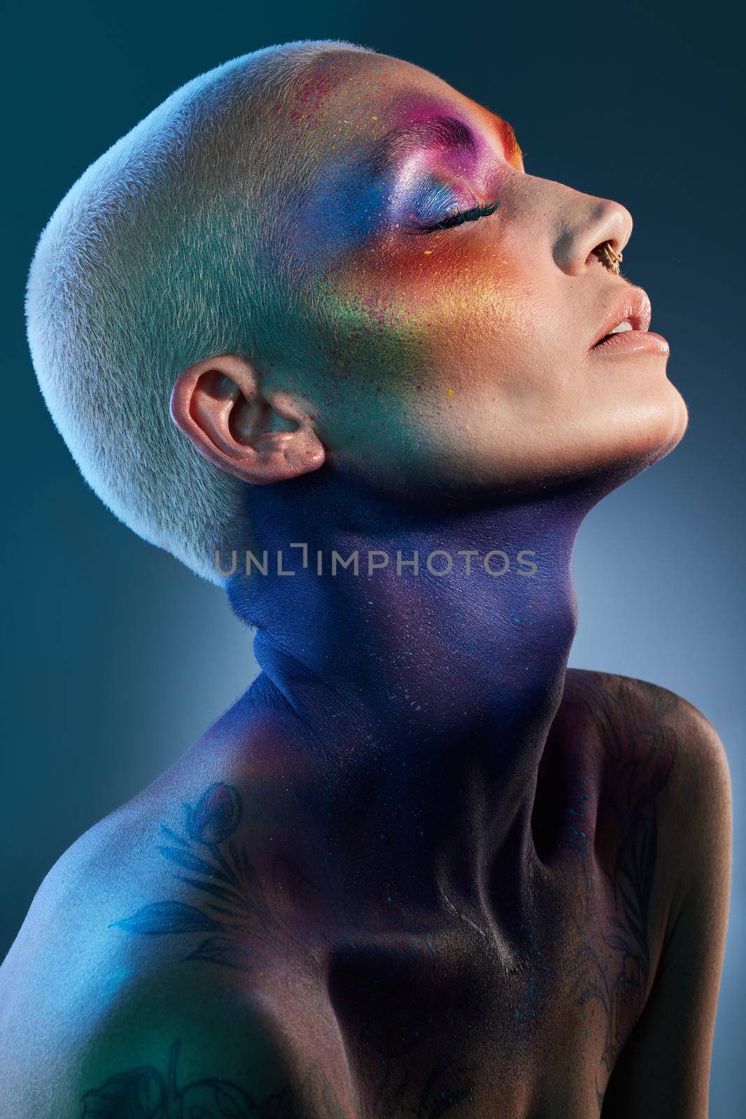 Studio shot of a young woman posing with multi-coloured paint on her face.