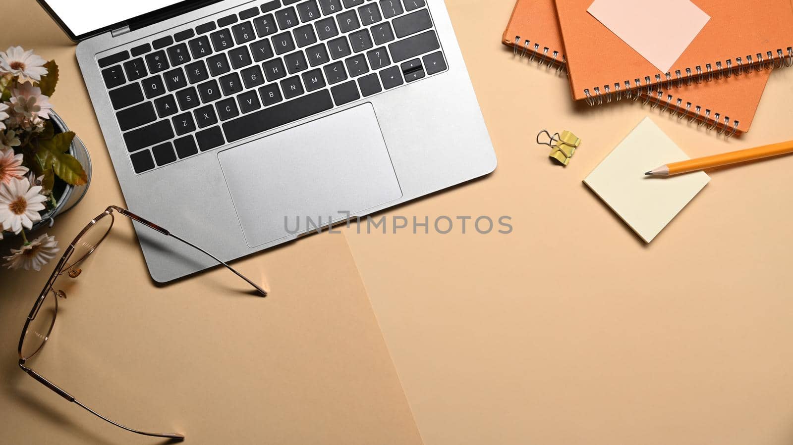 Stylish workplace, computer laptop, glasses, notebook and sticky note on beige background.