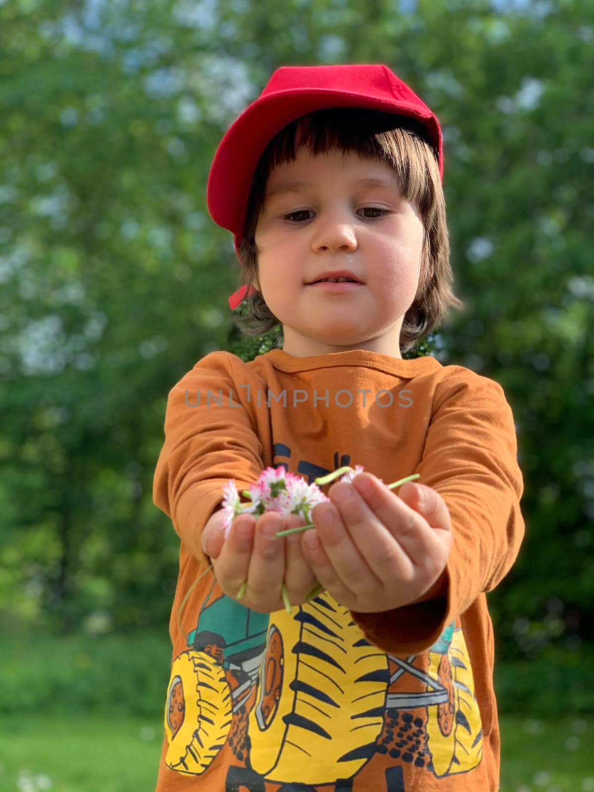 Portrait of a 5 year old boy in the park holding flowers in his hands . High quality photo