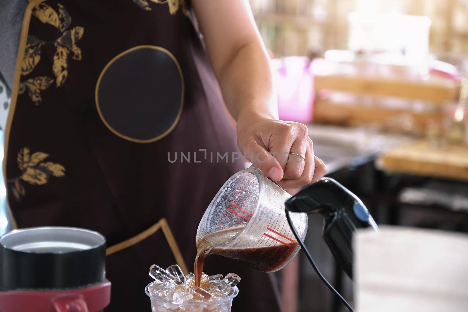 A female employee pours coffee into a plastic cup for customers.