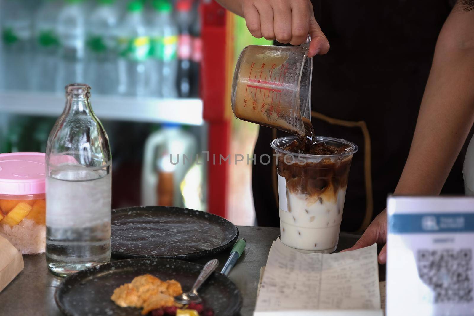 Employees are putting coffee into glasses to make latte for customers