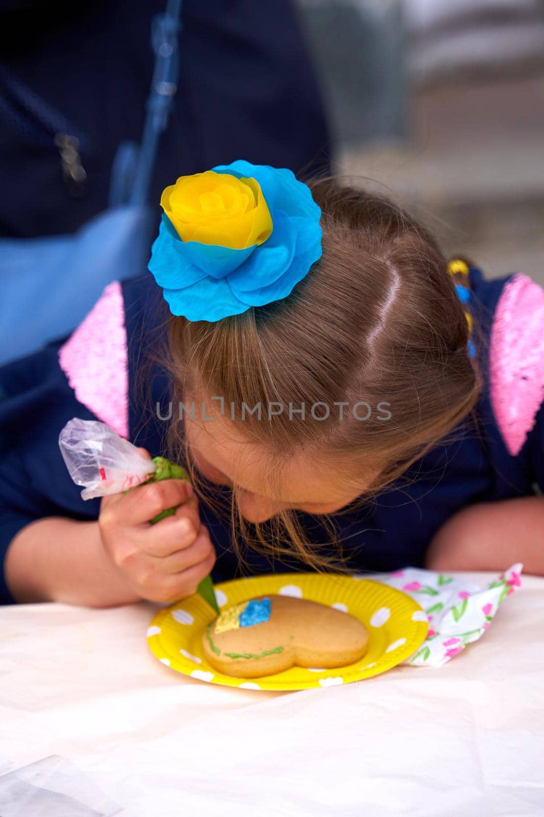 Vyshyvanka day in Ukraine. Kid painting Ukrainian flag in shape of heart on gingerbread. Dnipro, Ukraine - 05.19.2022