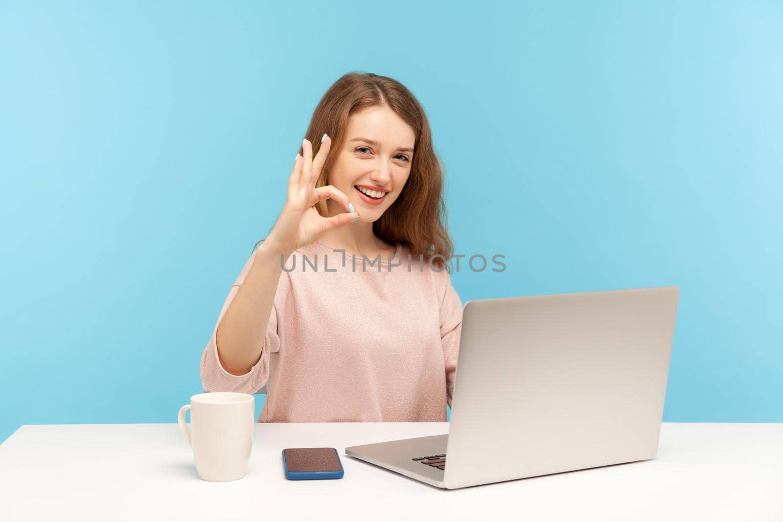 Emotional young woman working on laptop on blue background. by Khosro1