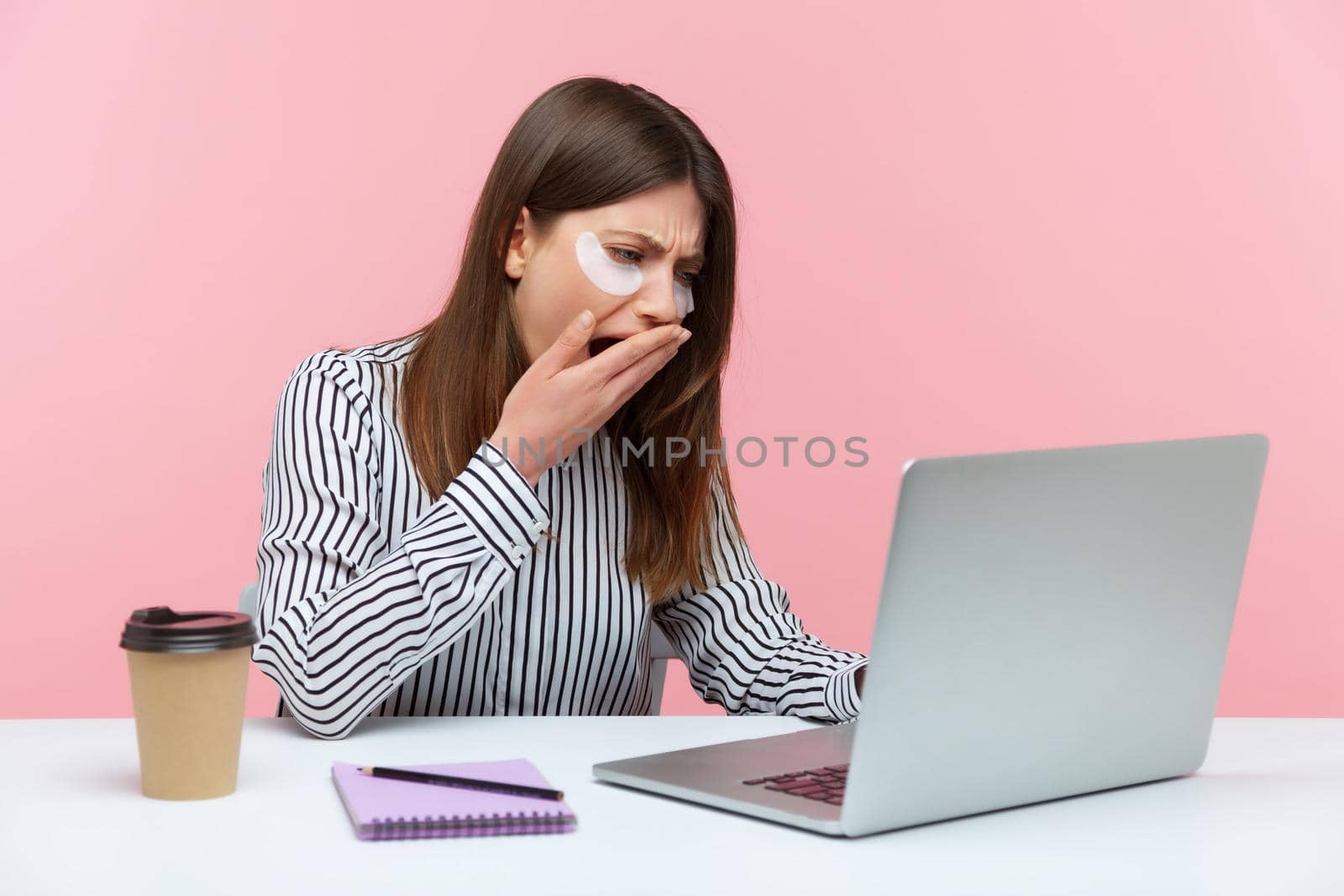 Emotional young woman sitting and working on office with pink background. by Khosro1