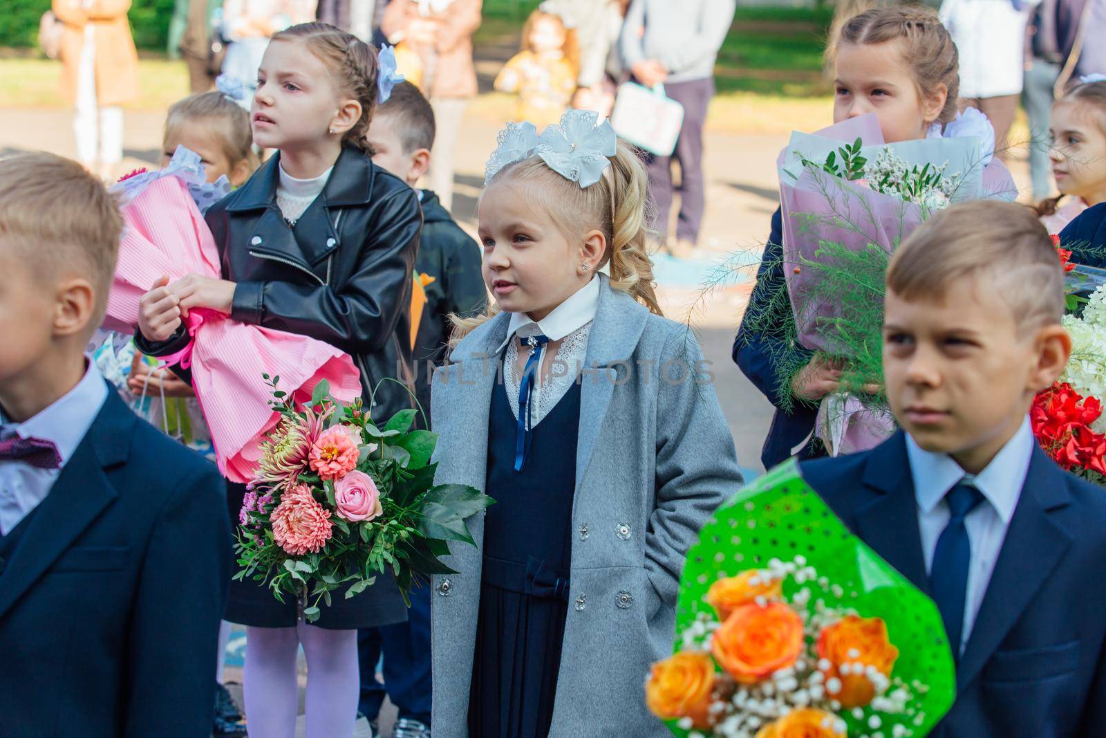 NOVOKUZNETSK, KEMEROVO REGION, RUSSIA - SEP, 1, 2021: Meeting with the first-grade pupils and teacher at schoolyard. The day of knowledge in Russia.