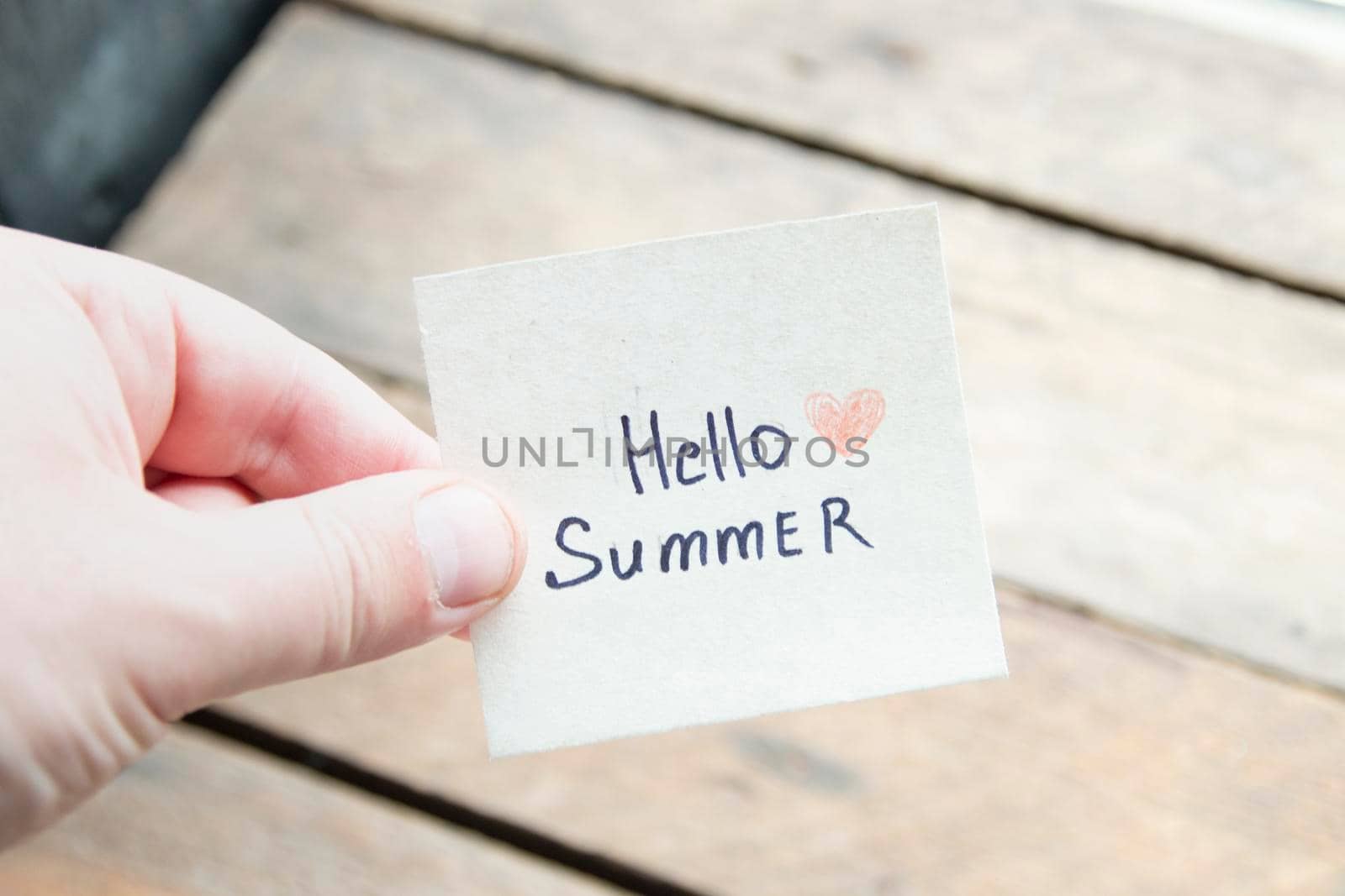 Hello summer. Creative concept. Hand holding a tag with the inscription. by Markgraf