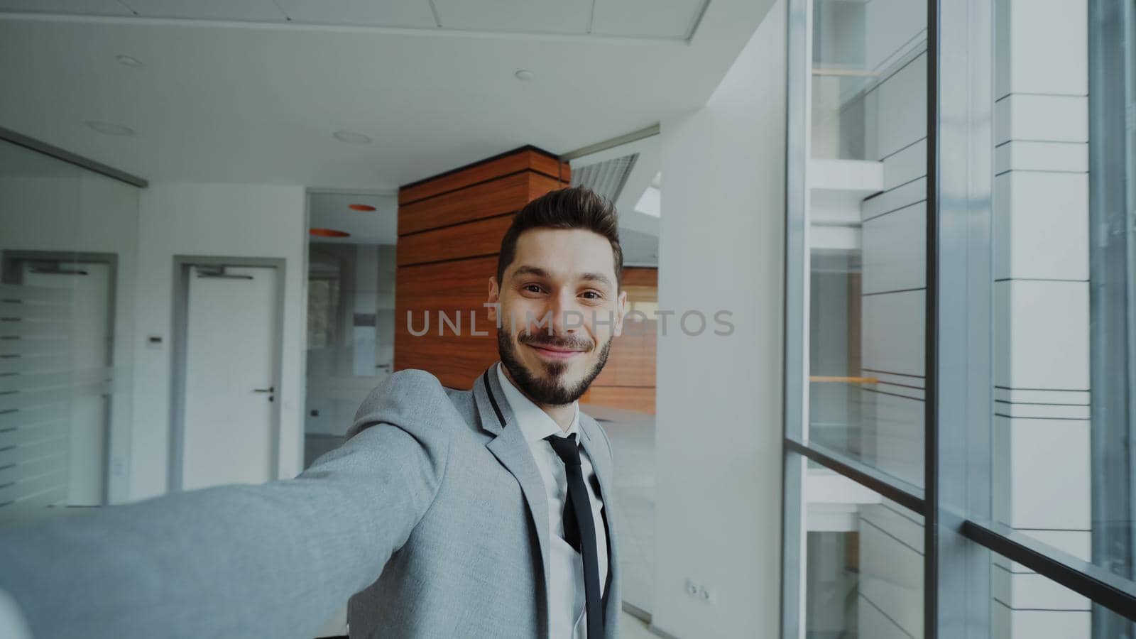 POV of young businessman in suit taking a selfie photo and have fun in modern office by silverkblack